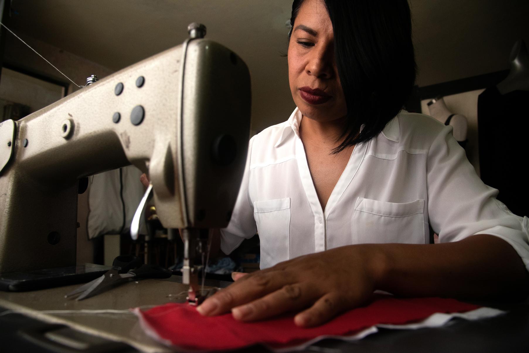 Una señora maquilando unas prendas con una máquina de coser.