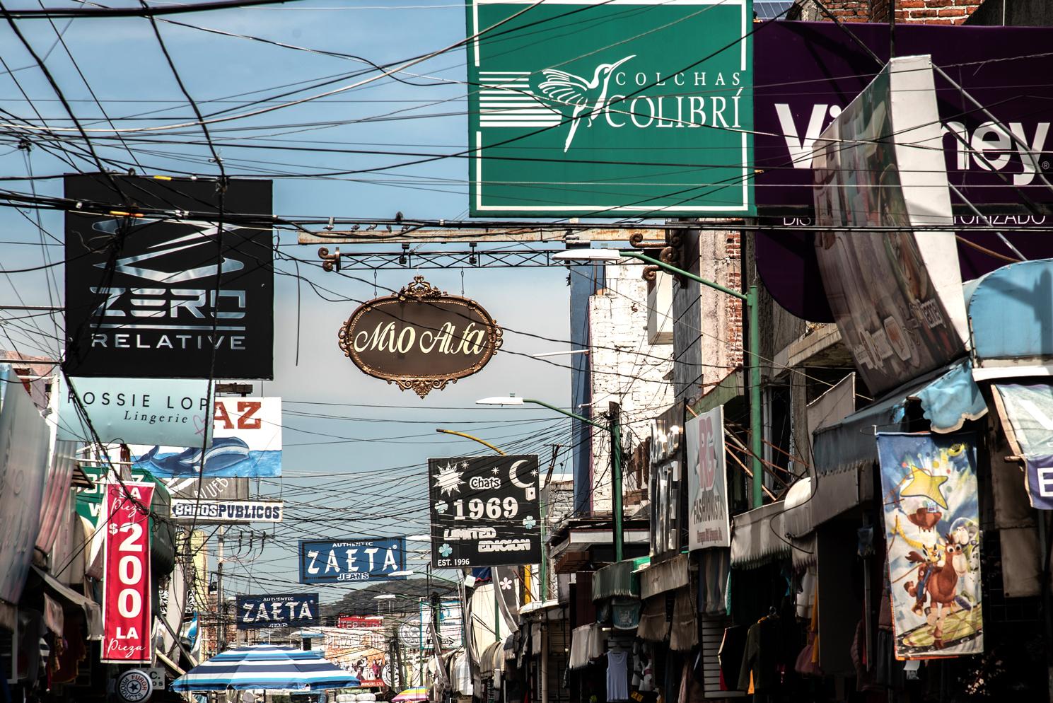 Letreros en la calle de diferentes locales que venden ropa